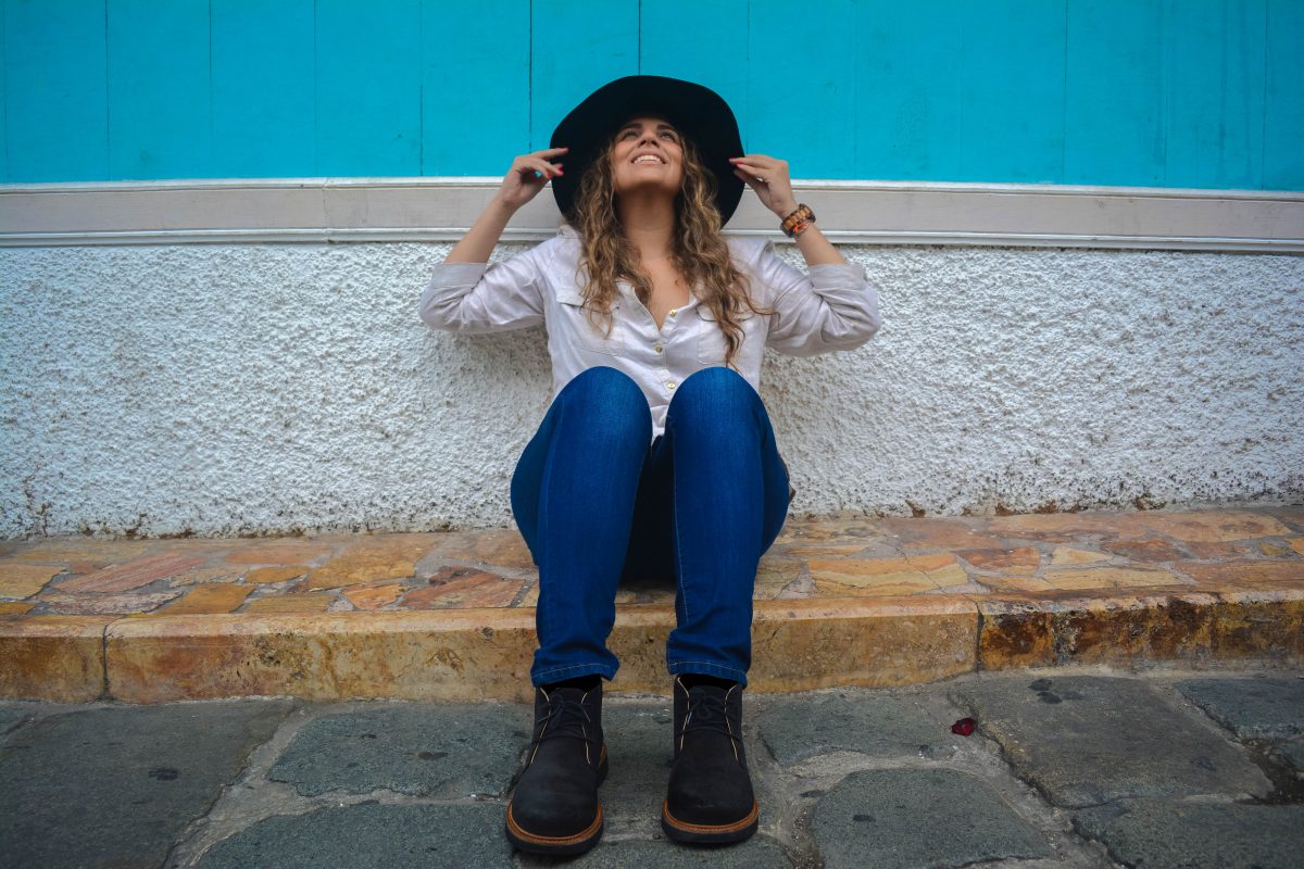 Girl sitting on the street wearing hat and shoes